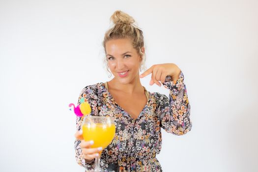 Pretty blonde woman in a flowery dress with a cocktail on white background