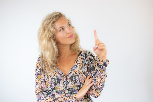 Pretty blonde woman in a flowery dress gesturing on white background