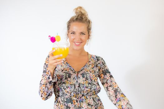 Pretty blonde woman in a flowery dress with a cocktail on white background