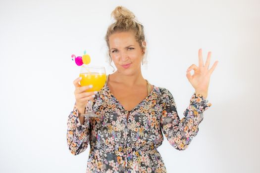 Pretty blonde woman in a flowery dress with a cocktail on white background