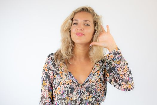 Pretty blonde woman in a flowery dress gesturing on white background