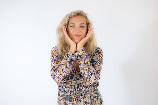 Pretty blonde woman in a flowery dress gesturing on white background