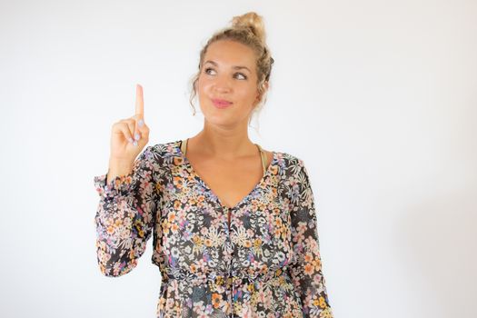 Pretty blonde woman in a flowery dress gesturing on white background