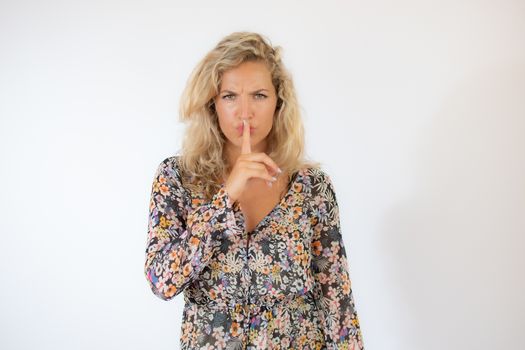 Pretty blonde woman in a flowery dress gesturing on white background