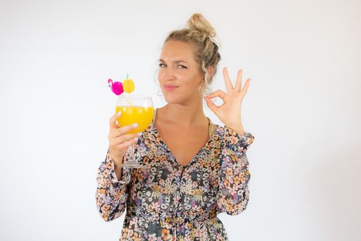 Pretty blonde woman in a flowery dress with a cocktail on white background