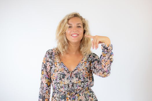 Pretty blonde woman in a flowery dress gesturing on white background