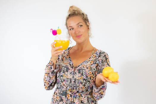 Pretty blonde woman in a flowery dress with a cocktail on white background