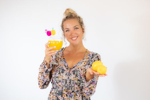 Pretty blonde woman in a flowery dress with a cocktail on white background