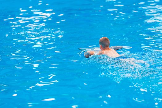 Happy little boy swimming with dolphins in Dolphinarium. Swimming, bathing and communication with dolphins.