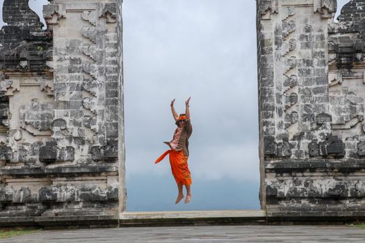 Bali, Indonesia. Traveler man jumping with energy and happiness in the gate of heaven. Lempuyang temple.