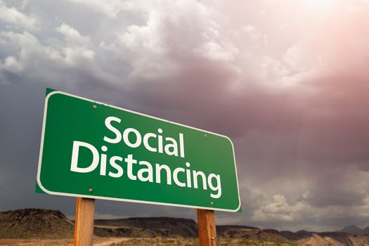 Social Distancing Green Road Sign Against Ominous Stormy Cloudy Sky.