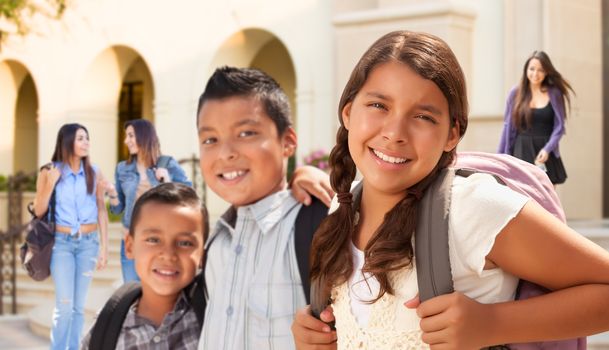 Young Hispanic Student Children Wearing Backpacks On School Campus.