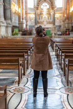Lyon, France -- November 6, 2017 -- A photographer focuses her camera to get a shot in a church. Editorial Use Only