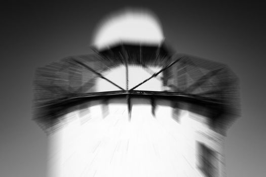 Black and white image of an old 19th century Georgian lighthouse at Burry Port, Carmarthenshire, Wales, UK with a zoom burst blur effect