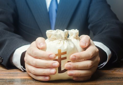 Businessman covers with hands turkish lira money bags. Accumulation of funds, bank loan. Investments. Corrupt schemes. Profit collection and tax withholding. Hit jackpot. Capital. Budget absorption