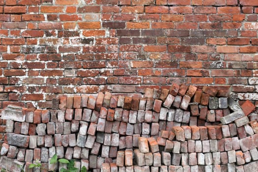 Old distressed red brick wall background texture with a pile of bricks in the foreground