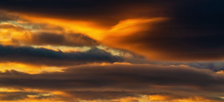 Panorama view of dramatic clouds illuminated rising of sun floating in sky to change weather. Soft focus, defocus and motion blur landscape. Impressive multicolored cloudscape and meteorology background.