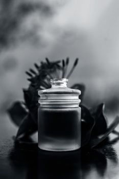 Close up of red colored pentas flower or Egyptian Star Flower or jasmine on wooden surface with its extracted essential oil in a transparent bottle.