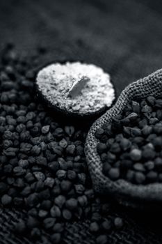 Close up of a jut bag full of chickpeas or grams in it and its floor or besan ka atta in a clay bowl on brown colored surface.