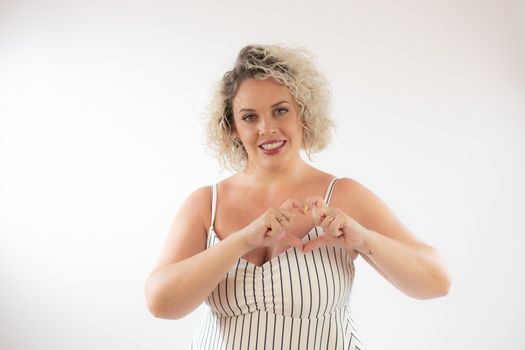 Blonde young woman making heart figure with her hands