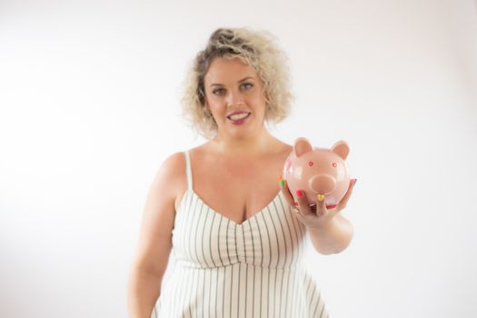 Blonde young woman with a piggy bank