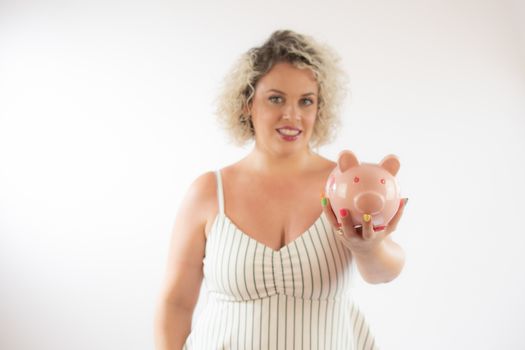 Blonde young woman with a piggy bank