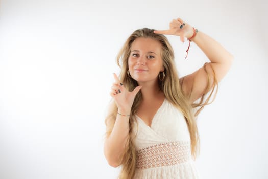 Pretty blonde girl in a white dress making the portrait gesture