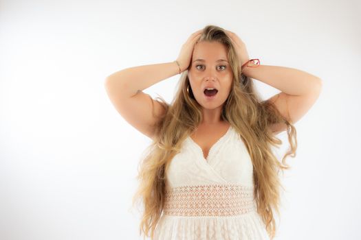 Pretty blonde girl in a white dress with the gesture of surprise