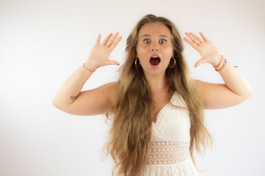 Pretty blonde girl in a white dress with surprised gesture