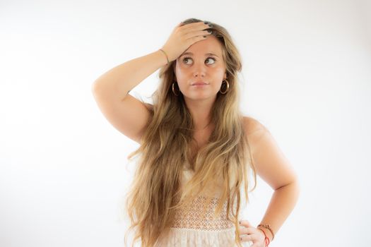 Pretty blonde girl in a white dress with the gesture of concern on her face