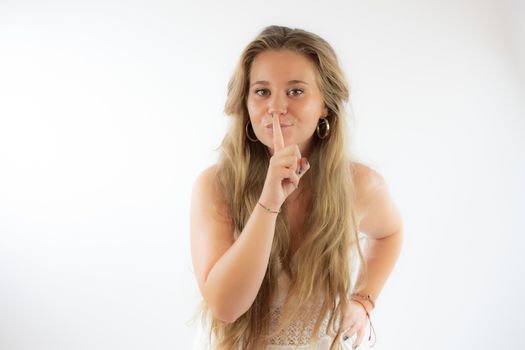 Pretty blonde girl in a white dress making silence gesture