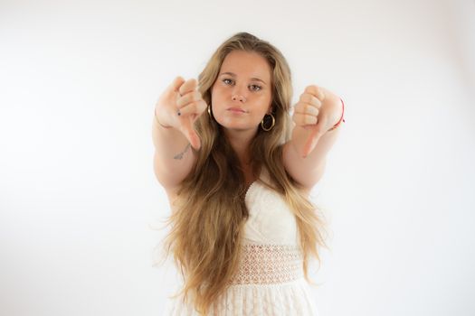 Pretty blonde girl in a white dress making fingers down gesture