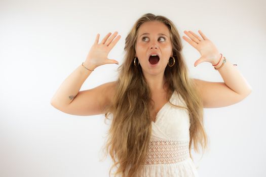 Pretty blonde girl in a white dress with surprised gesture