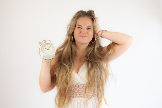 Pretty blonde girl in a white dress showing a clock