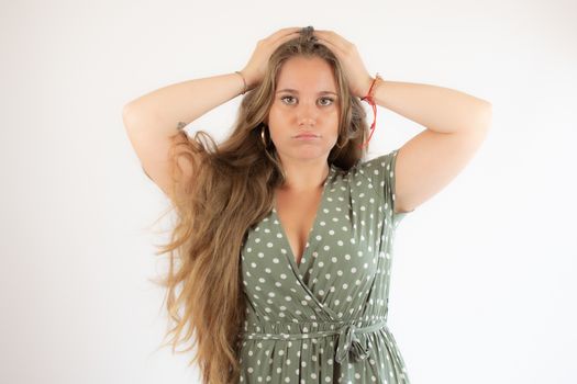 Pretty blonde girl in a green dress with the gesture of concern