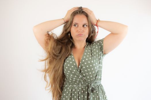 Pretty blonde girl in a green dress with the gesture of concern