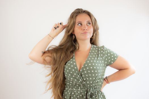 Pretty blonde girl in a green dress with the gesture of concern