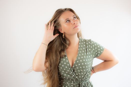 Pretty blonde girl in a green dress making the silence gesture