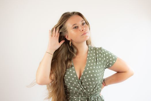 Pretty blonde girl in a green dress making the silence gesture