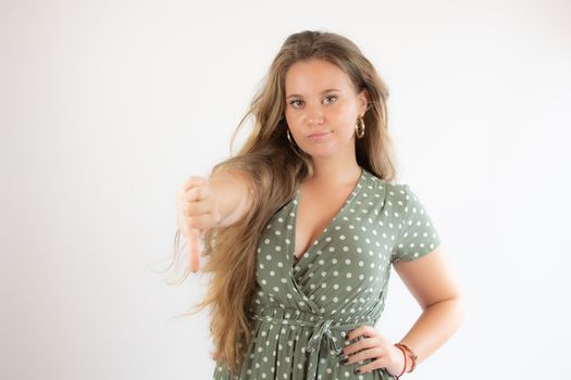 Pretty blonde girl in a green dress making finger down gesture