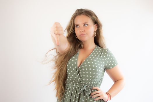 Pretty blonde girl in a green dress making finger down gesture