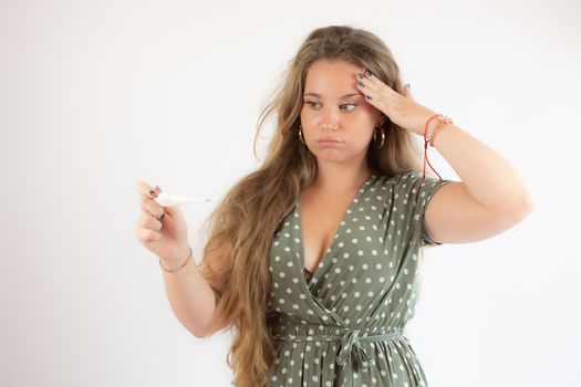 Pretty blonde girl in a green dress looking the test with the gesture of concern