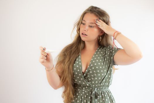 Pretty blonde girl in a green dress looking the test with the gesture of concern