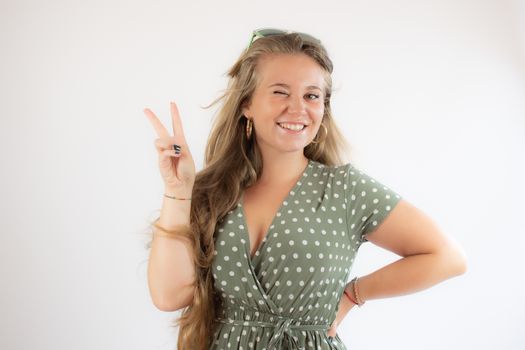 Portrait of a pretty young girl in green dress making funny gesture