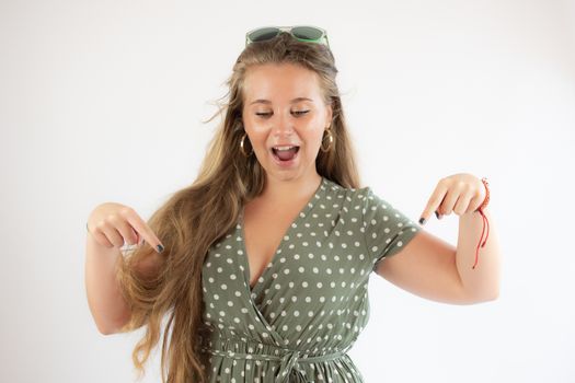 Pretty blonde girl in a green dress pointing with her fingers