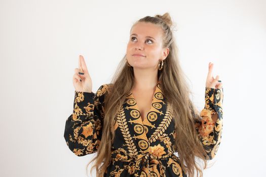 Pretty blonde girl in black gold dress with fingers crossed