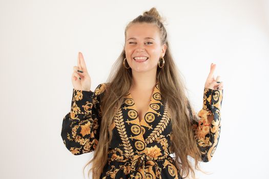 Pretty blonde girl in black gold dress with fingers crossed