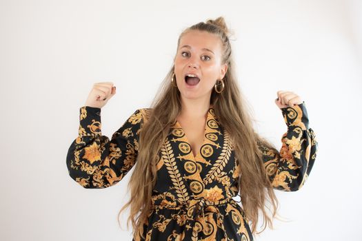 Pretty blonde girl in gold black dress making victory gesture