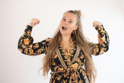 Pretty blonde girl in gold black dress making victory gesture