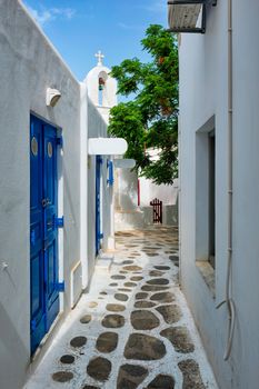 Picturesque scenic narrow Greek streets with traditional whitewashed houses with blue doors windows of Mykonos town in famous tourist attraction Mykonos island, Greece